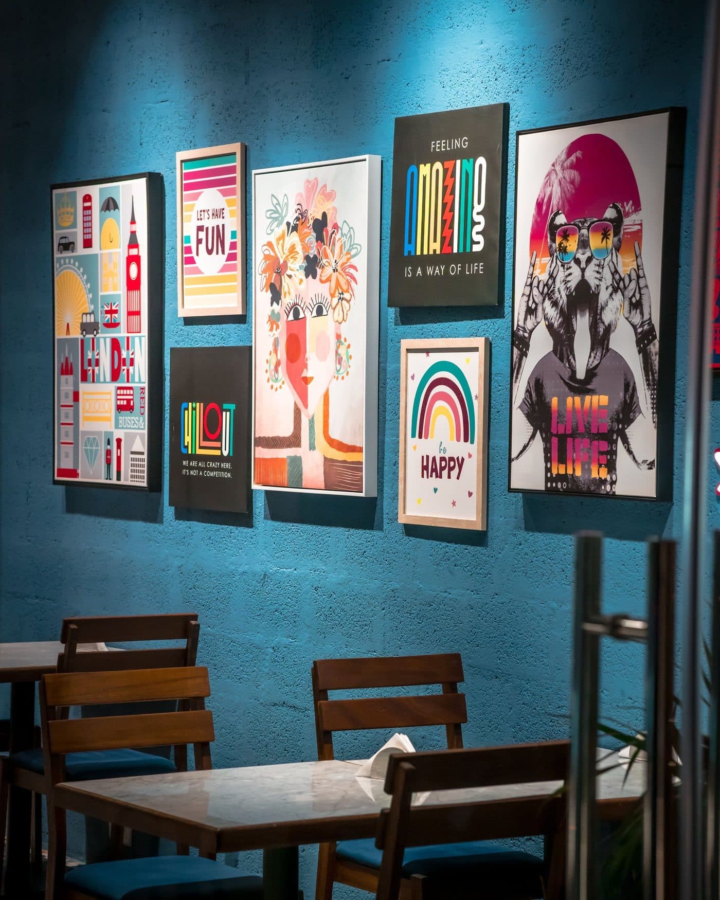 Framed art prints hung in a grid across a deep teal wall